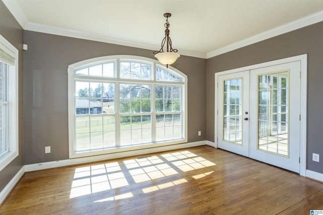 unfurnished dining area with french doors, crown molding, baseboards, and wood finished floors