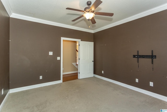 spare room with ornamental molding, a textured ceiling, carpet flooring, baseboards, and ceiling fan