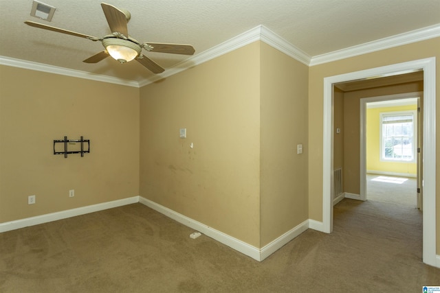 empty room featuring crown molding, carpet flooring, baseboards, and visible vents