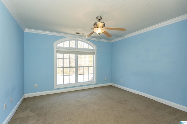 carpeted spare room featuring a ceiling fan, crown molding, baseboards, and visible vents