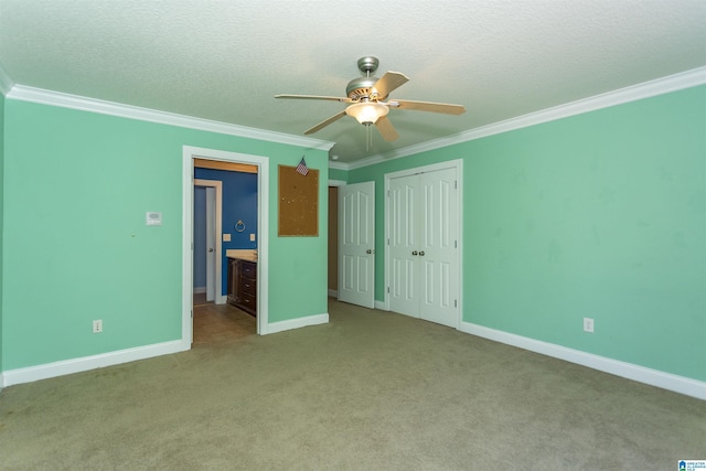 unfurnished bedroom featuring a closet, a textured ceiling, ornamental molding, and carpet flooring