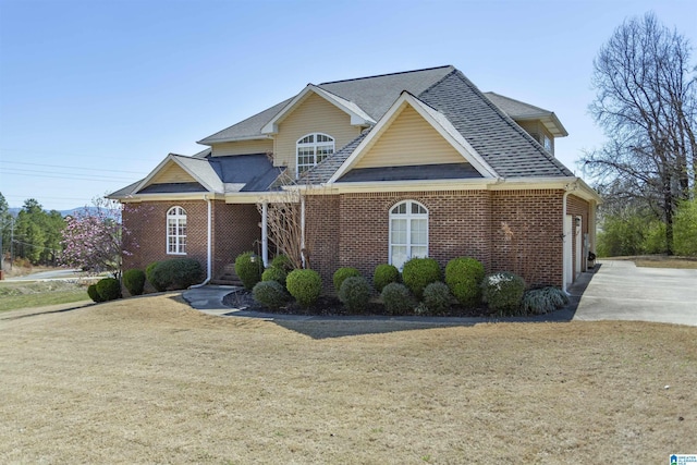 traditional-style house with a front lawn, brick siding, and roof with shingles