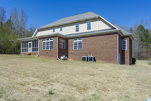 back of house featuring a lawn, brick siding, a sunroom, and crawl space