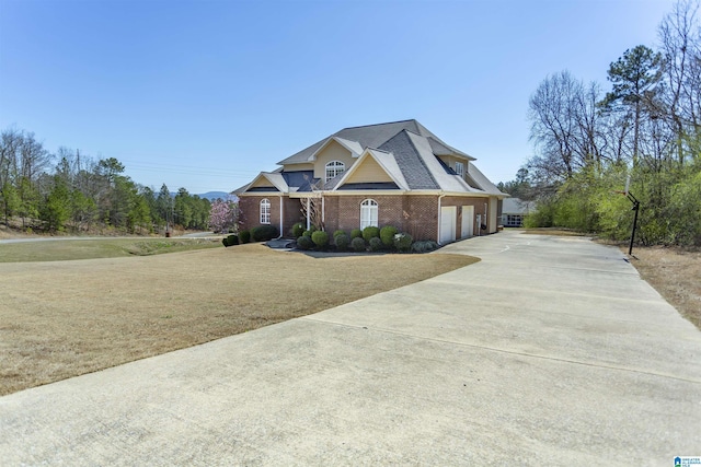 view of front facade with an attached garage, a shingled roof, concrete driveway, a front lawn, and brick siding