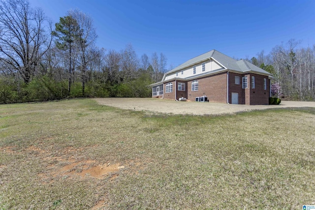 view of side of property with brick siding and a lawn