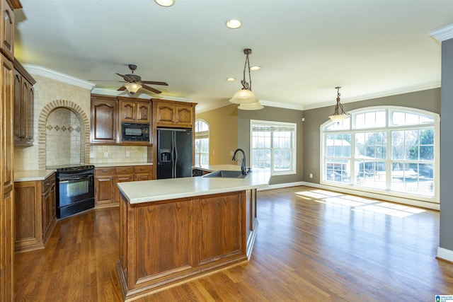 kitchen featuring a sink, black appliances, dark wood-style floors, and light countertops