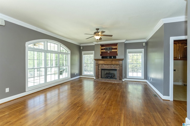 unfurnished living room featuring a brick fireplace, wood finished floors, baseboards, and a healthy amount of sunlight