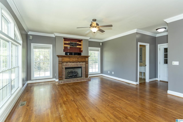 unfurnished living room with wood finished floors, visible vents, baseboards, a fireplace, and crown molding