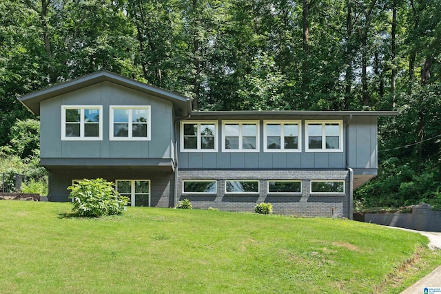 view of front of house with brick siding, board and batten siding, and a front yard