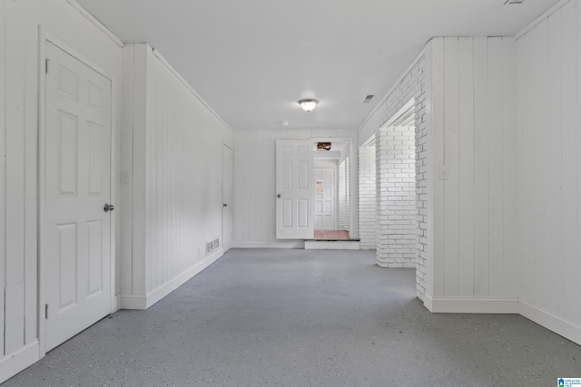 empty room with brick wall, baseboards, and visible vents