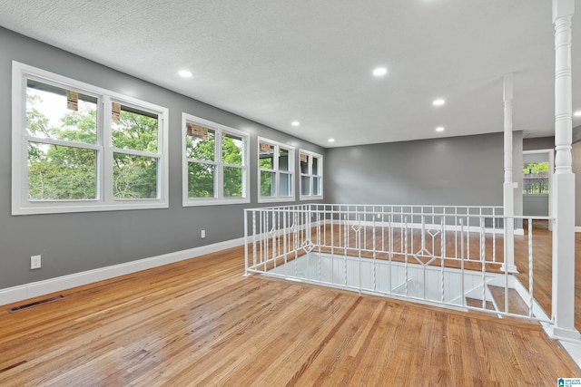 spare room featuring baseboards, visible vents, wood finished floors, ornate columns, and recessed lighting