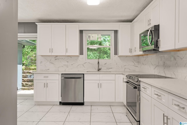 kitchen with decorative backsplash, white cabinets, appliances with stainless steel finishes, marble finish floor, and a sink