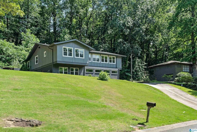 view of front facade with driveway, a front lawn, and board and batten siding