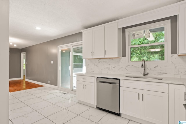 kitchen featuring marble finish floor, stainless steel dishwasher, a sink, and light countertops