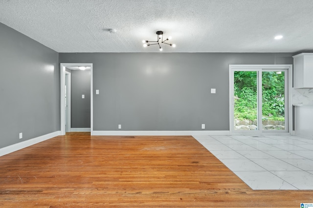 empty room featuring a textured ceiling, marble finish floor, and baseboards