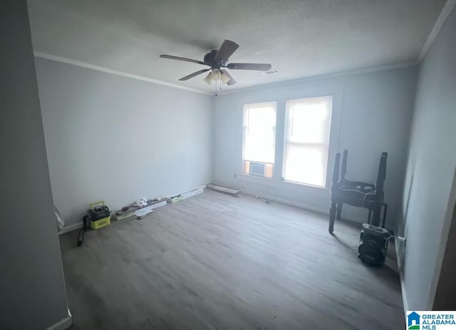 unfurnished room with wood finished floors, visible vents, baseboards, a ceiling fan, and ornamental molding