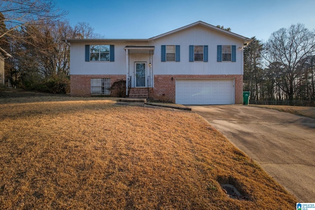 raised ranch with a garage, brick siding, driveway, and a front lawn