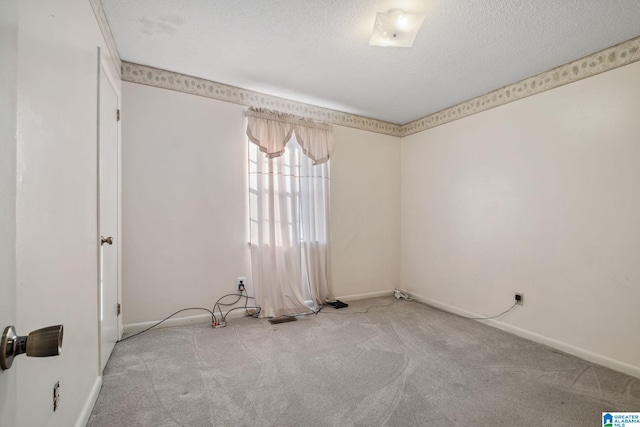 empty room featuring carpet flooring, a textured ceiling, and baseboards