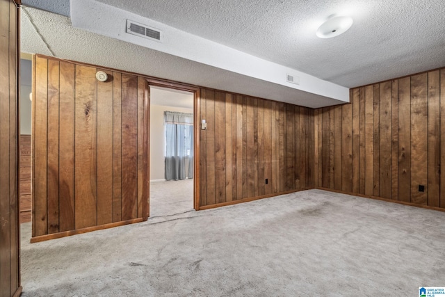 basement featuring carpet floors, wood walls, and visible vents