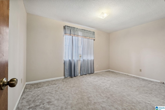 empty room featuring carpet, baseboards, and a textured ceiling