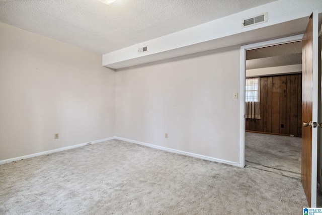 unfurnished room featuring carpet, visible vents, a textured ceiling, and baseboards