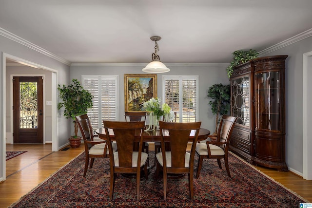 dining room featuring crown molding, light wood-style flooring, and baseboards