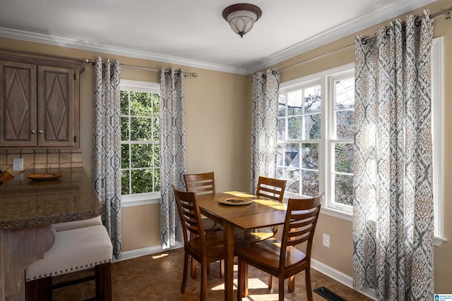 dining room featuring ornamental molding, dark tile patterned floors, visible vents, and baseboards