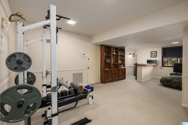 exercise room featuring carpet floors, a wainscoted wall, and visible vents