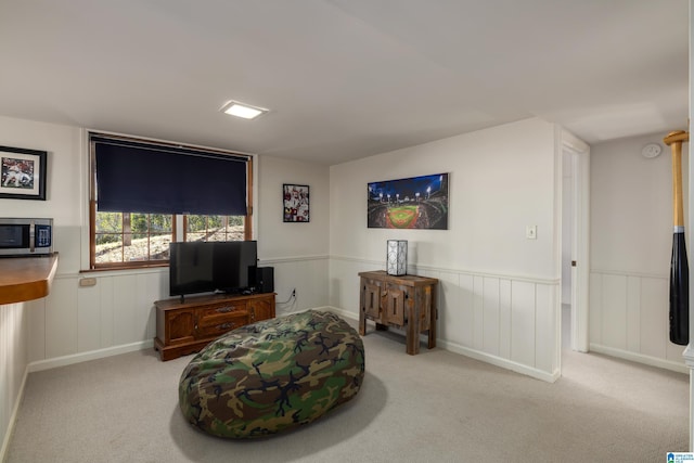 living area featuring a wainscoted wall and carpet