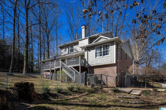 back of property featuring a fenced front yard, brick siding, stairs, a gate, and a chimney