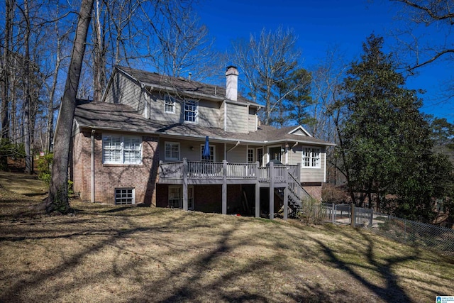 rear view of house featuring brick siding, a chimney, a lawn, stairway, and fence