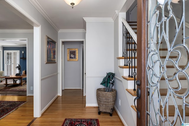 entryway featuring stairs, ornamental molding, light wood-type flooring, and baseboards