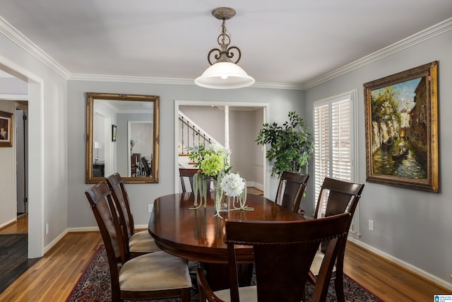 dining room with crown molding, baseboards, and wood finished floors