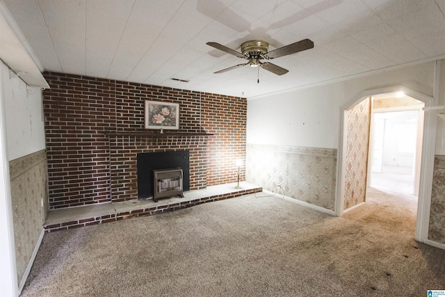 unfurnished living room with carpet floors, a wainscoted wall, visible vents, and a wood stove