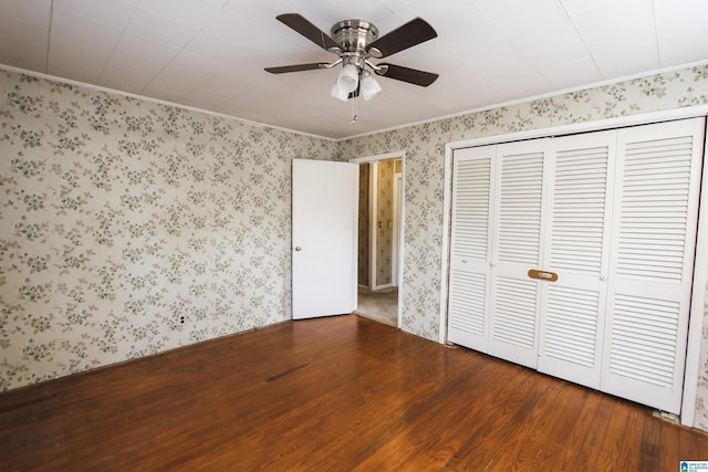 unfurnished bedroom featuring a closet, wood finished floors, a ceiling fan, and wallpapered walls