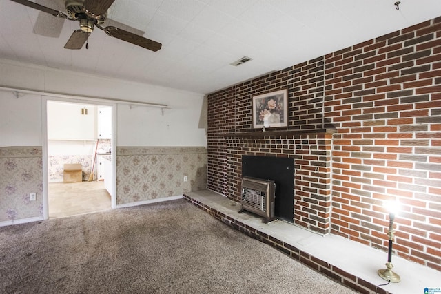 unfurnished living room featuring carpet flooring, visible vents, wainscoting, a wood stove, and wallpapered walls