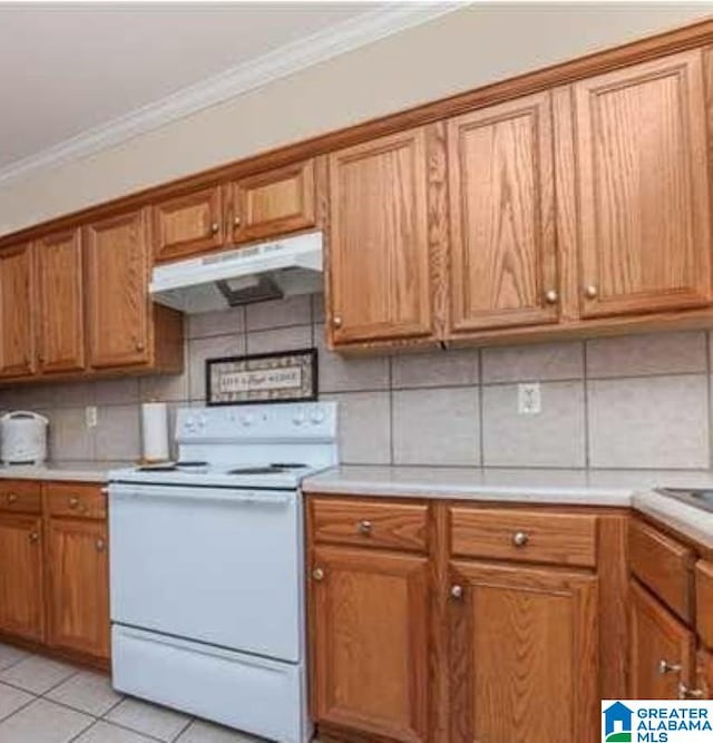 kitchen with under cabinet range hood, ornamental molding, backsplash, brown cabinets, and white range with electric cooktop