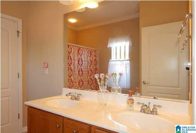 bathroom with double vanity, crown molding, a sink, and a shower with shower curtain