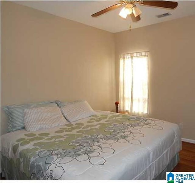 bedroom featuring a ceiling fan, baseboards, visible vents, and wood finished floors