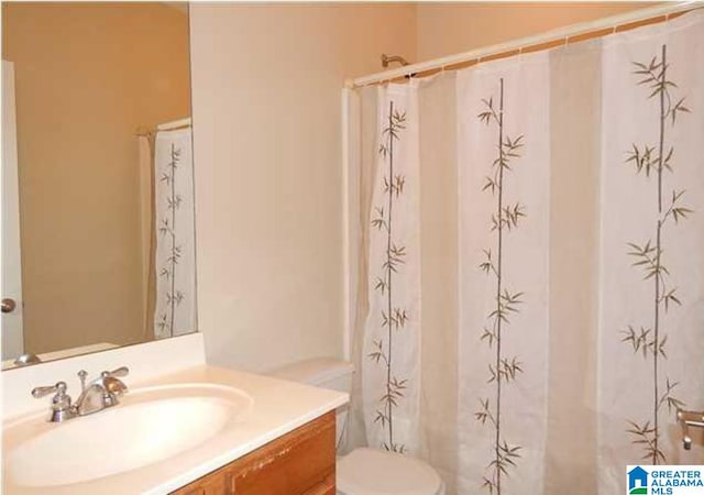 bathroom with curtained shower, vanity, and toilet