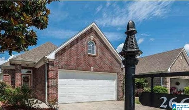 view of front of home featuring a garage, driveway, and brick siding