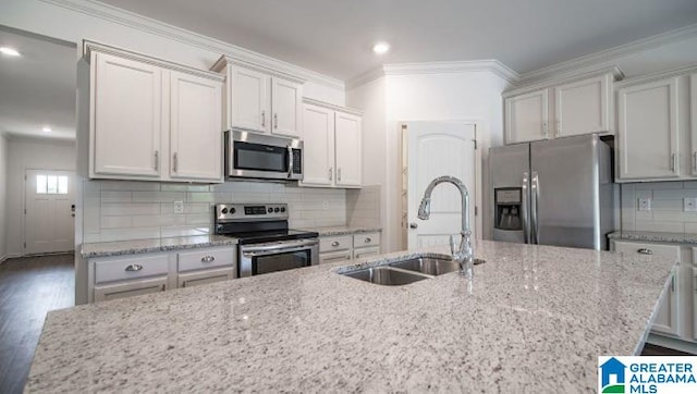 kitchen with dark wood-style flooring, stainless steel appliances, backsplash, ornamental molding, and a sink