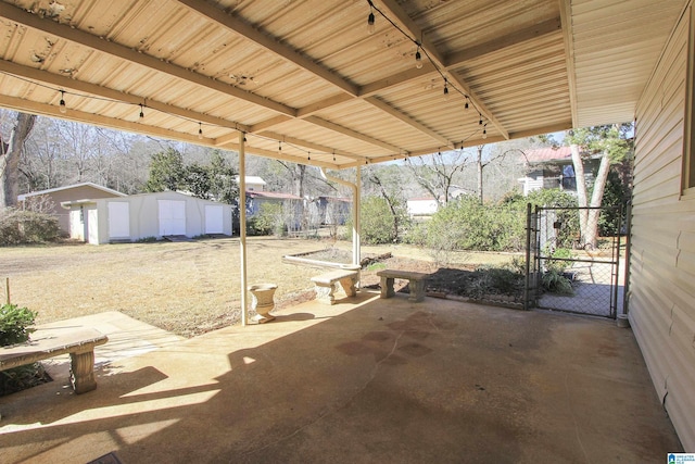 view of patio featuring a gate, fence, and an outbuilding