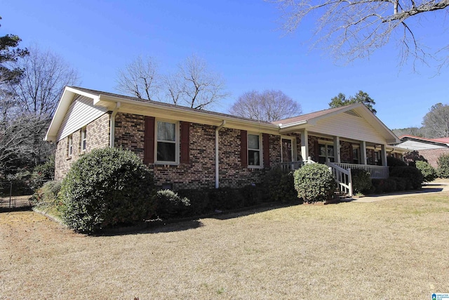 single story home featuring brick siding, a front lawn, and a porch