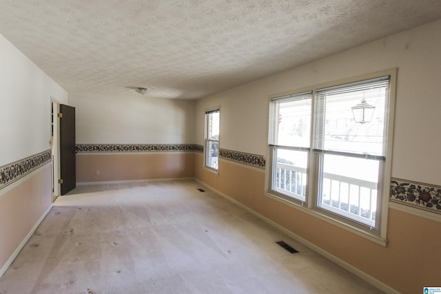 spare room featuring visible vents, a textured ceiling, and baseboards