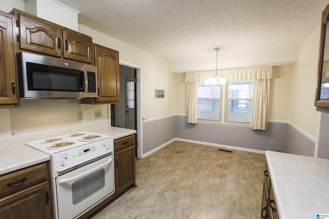 kitchen with a textured ceiling, light wood-style floors, light countertops, white range with electric stovetop, and stainless steel microwave