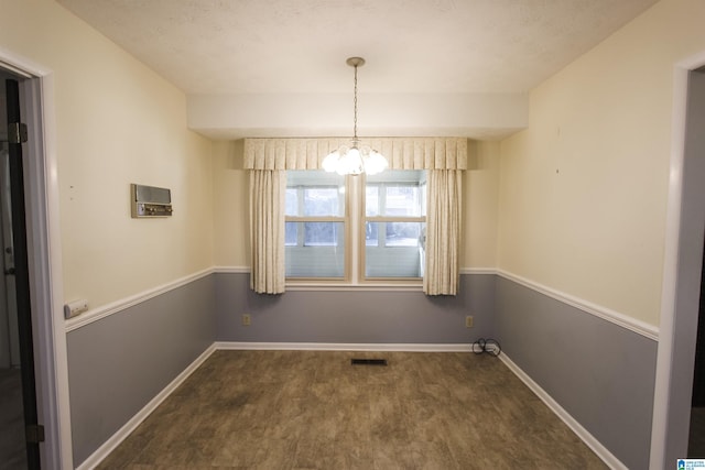 unfurnished dining area with a chandelier, visible vents, baseboards, and wood finished floors