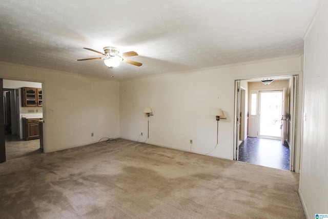 carpeted spare room with ornamental molding and a ceiling fan