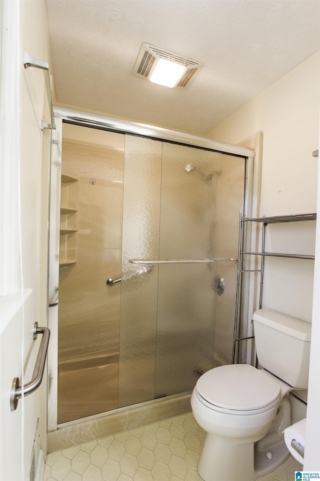 full bathroom featuring toilet, a shower stall, and visible vents