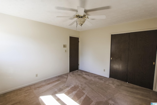 unfurnished bedroom featuring carpet floors, a closet, a ceiling fan, and baseboards